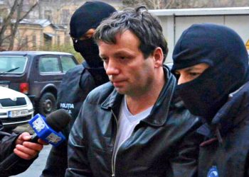 Marcel Lazar Lehel, 40, is escorted by masked policemen in Bucharest, after being arrested in Arad, 550 km (337 miles) west of Bucharest January 22, 2014. Lehel is allegedly the hacker using the nicknames "Guccifer" and "The Small Fume" and is suspected to have broken into several e-mail accounts of various politicians and celebrities and the head of Romania's Intelligence Service George Maior. REUTERS/Mediafax/Silviu Matei (ROMANIA - Tags: CRIME LAW) THIS IMAGE HAS BEEN SUPPLIED BY A THIRD PARTY. IT IS DISTRIBUTED, EXACTLY AS RECEIVED BY REUTERS, AS A SERVICE TO CLIENTS. ROMANIA OUT. NO COMMERCIAL OR EDITORIAL SALES IN ROMANIA