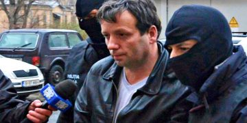 Marcel Lazar Lehel, 40, is escorted by masked policemen in Bucharest, after being arrested in Arad, 550 km (337 miles) west of Bucharest January 22, 2014. Lehel is allegedly the hacker using the nicknames "Guccifer" and "The Small Fume" and is suspected to have broken into several e-mail accounts of various politicians and celebrities and the head of Romania's Intelligence Service George Maior. REUTERS/Mediafax/Silviu Matei (ROMANIA - Tags: CRIME LAW) THIS IMAGE HAS BEEN SUPPLIED BY A THIRD PARTY. IT IS DISTRIBUTED, EXACTLY AS RECEIVED BY REUTERS, AS A SERVICE TO CLIENTS. ROMANIA OUT. NO COMMERCIAL OR EDITORIAL SALES IN ROMANIA