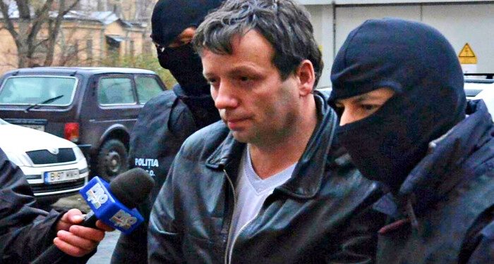 Marcel Lazar Lehel, 40, is escorted by masked policemen in Bucharest, after being arrested in Arad, 550 km (337 miles) west of Bucharest January 22, 2014. Lehel is allegedly the hacker using the nicknames "Guccifer" and "The Small Fume" and is suspected to have broken into several e-mail accounts of various politicians and celebrities and the head of Romania's Intelligence Service George Maior. REUTERS/Mediafax/Silviu Matei (ROMANIA - Tags: CRIME LAW) THIS IMAGE HAS BEEN SUPPLIED BY A THIRD PARTY. IT IS DISTRIBUTED, EXACTLY AS RECEIVED BY REUTERS, AS A SERVICE TO CLIENTS. ROMANIA OUT. NO COMMERCIAL OR EDITORIAL SALES IN ROMANIA