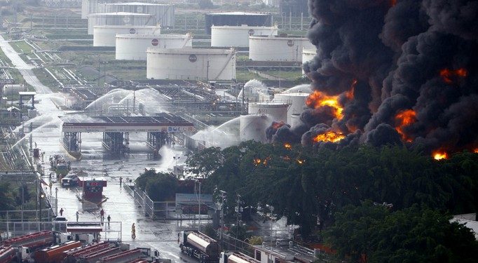 Firefighters try to extinguish a fire at a oil refinery in Puerto La Cruz August 11, 2013. Lightning set fire to a storage tank at Venezuela's Puerto La Cruz oil refinery on Sunday, the president said, and residents were moved out of the immediate area while local media showed images of thick black smoke rising from the facility. Thunderstorms this weekend have drenched much of the South American OPEC nation, which has suffered repeated accidents at its oil refineries in recent years. Lightning bolts ignited two storage tanks at a different refinery just last year. REUTERS/Stringer (VENEZUELA - Tags: DISASTER BUSINESS COMMODITIES TPX IMAGES OF THE DAY)