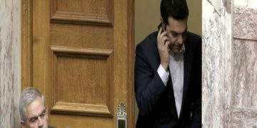 Greece's Prime Minister Alexis Tsipras speaks from his mobile phone during emergency Parliament session for the governments proposed referendum in Athens, Saturday, June 27, 2015. Greece's place in the euro currency bloc looked increasingly shaky on Saturday, when eurozone countries rejected a monthlong extension to its bailout program and the prime minister called for a risky popular vote on the country's financial future. (AP Photo/Petros Karadjias)