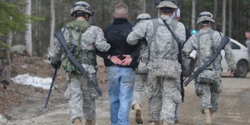 Alaska National Guard Soldiers escort a protestor away after assisting Anchorage Police to calm or detain rioters as part of the training scenario of exercise Vigilant Guard Ft. Richardson, Alaska, Wednesday April 28, 2010. Vigilant Guard is an annual, disaster-based training scenario that tests the coordination of National Guard units with local, state, regional, and national disaster preparedness organizations. (U.S. Air Force photo by Tech. Sgt. Brian E. Christiansen, North Carolina National Guard) (Released)