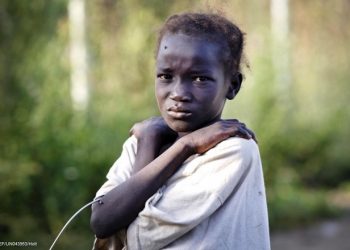 On 22 October 2016, a young girl, who has just arrived from Leer, where there is heavy fighting, poses for a photograph at the gate of  the  UN Protection of Civilian Camp (POC) Bentiu, South Sudan. Recent fighting  in Leer between Governemnt forces and rebel groups have forced thousands more people into the UN camp in Bentiu that is now home to 105,000 people.