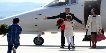 Johan Tarculovski, center, accompanied by his wife Sonja Tarculovska, right, is welcomed by his children upon his arrival at "Alexander the Great" airport near Macedonia's capital Skopje, on Thursday, April 11, 2013. Couple of thousands of people have gathered at the airport on Tuesday to welcome the return of Johan Tarculovski, the only Macedonian convicted by The Hague tribunal for war crimes committed during 2001 ethnic conflict. (AP Photo/(Boris Grdanoski)