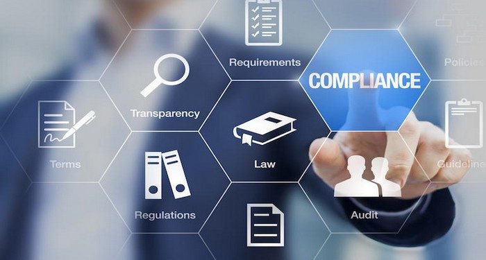 Compliance concept with icons for regulations, law, standards, requirements and audit on a virtual screen with a business person touching a button