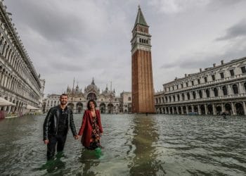 VENICE, ITALY - OCTOBER 29: A couple of tourists walk in "Piazza San Marco" on October 29, 2018 in Venice, Italy. Due to the exceptional level of the "acqua alta" or "High Tide" that reached 156 cm today, Venetian schools and hospitals were closed by the authorities, and citizens were advised against leaving their homes . (Photo by Stefano Mazzola/Awakening/Getty Images)