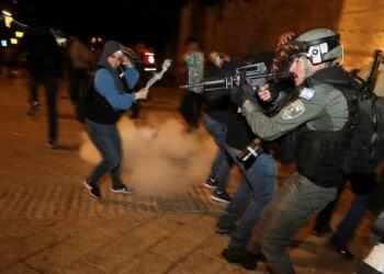 Israeli police officer stands in position as a stun grenade explodes by the gate to Jerusalem's Old City during clashes, as the Muslim holy fasting month of Ramadan continues, in Jerusalem April 24, 2021. REUTERS/Ammar Awad