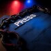 Freedom of the press and journalism concept. Blue journalist (press) vest in dark with backlight and fog. Shackles on vest. Selective focus