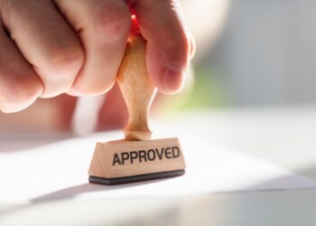 Businessman or notary public stamping approved stamp on document in meeting