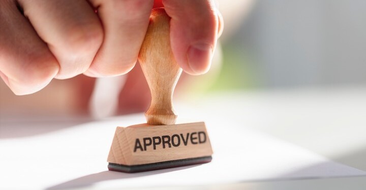 Businessman or notary public stamping approved stamp on document in meeting
