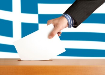 Hand with ballot and box on Flag of Greece