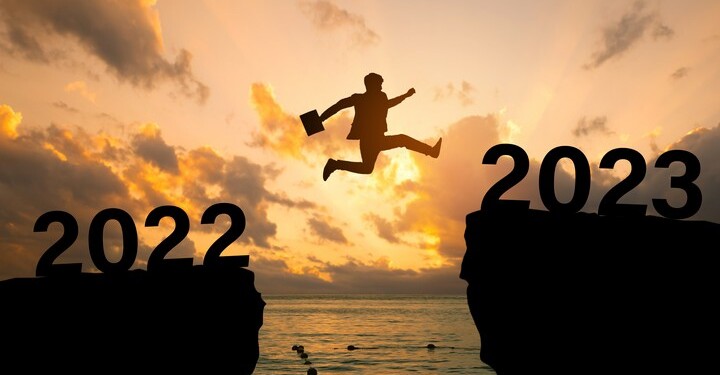 2023 new year concept, new year card.Silhouette of a businessman jumping on a cliff in 2023 over sea cliff at a beautiful sunset. business plan and success for 2023.