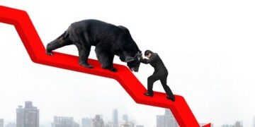 Businessman against black bear on red arrow downward trend line with sky cityscape background. Fight back bearish market concept.