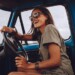 Portrait of young woman having fun while driving a car. Cheerful woman going on a road trip on a old truck.