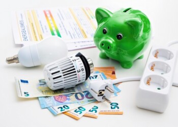 Energy cost, saving energy concept. Piggy bank with money, plug, bulb and radiator thermostat on white background