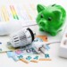 Energy cost, saving energy concept. Piggy bank with money, plug, bulb and radiator thermostat on white background