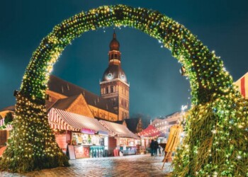 Riga, Latvia. Traditional Christmas Market On Dome Square With Riga Dome Cathedral. Famous Landmark In Winter Evening Night In Festive Illuminations Lighting