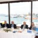 Άποψη από το Επίσημο Τραπέζι, από αριστερά προς τα δεξιά: 
Ο κύριος Γιώργος Ξυραδάκης Πρόεδρος της ένωσης χρηματοοικονομικών στελεχών Ναυτιλίας, ο κύριος Βώκος Θεόδωρος Διευθύνων Σύμβουλος Εκθέσεις Ποσειδώνια ΑΕ,     ο κύριος Φραγκούλης Κωστής Πρόεδρος του Propeller Club Port of Piraeus, o κύριος Κωστής Χατζηδάκης Υπουργός Εθνικής Οικονομίας και Οικονομικών, ο κύριος Βασίλειος Λογοθέτης μέλος του Δ.Σ. του Ναυτικού Επιμελητηρίου Ελλάδος, η κυρία Βιβή Κολλιοπούλου Πρόεδρος της Wista Hellas και στο βήμα ο ο κύριος Γεώργιος Σπ. Αλεξανδράτος Πρόεδρος της Ναυτιλιακής Λέσχης Πειραιώς, κατά την διάρκεια της ομιλίας του.