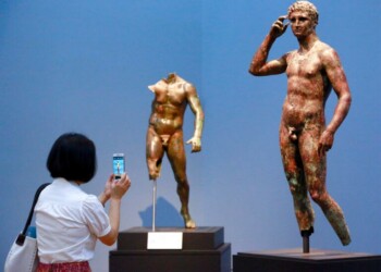 In this Monday, July 27, 2015 photo, reporter Sookee Chung takes a photo of a sculpture titled "Statue of a Victorious Youth, 300-100 B.C." at the J. Paul Getty Museum in Los Angeles. The J. Paul Getty Museum in Los Angeles has vowed to assert its right to keep an important Greek statue after Italy's highest court rejected its appeal of a ruling ordering the artwork to be returned to Italy. The ANSA news agency said Tuesday that the Court of Cassation rejected the appeal outright earlier this week. "Victorious Youth," a nearly life-sized bronze dating from 300 B.C. to 100 B.C., is one of the highlights of the Getty collection. (AP Photo/Nick Ut, File )