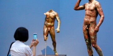 In this Monday, July 27, 2015 photo, reporter Sookee Chung takes a photo of a sculpture titled "Statue of a Victorious Youth, 300-100 B.C." at the J. Paul Getty Museum in Los Angeles. The J. Paul Getty Museum in Los Angeles has vowed to assert its right to keep an important Greek statue after Italy's highest court rejected its appeal of a ruling ordering the artwork to be returned to Italy. The ANSA news agency said Tuesday that the Court of Cassation rejected the appeal outright earlier this week. "Victorious Youth," a nearly life-sized bronze dating from 300 B.C. to 100 B.C., is one of the highlights of the Getty collection. (AP Photo/Nick Ut, File )