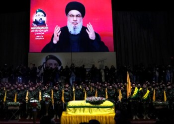 Hezbollah fighters stand behind the coffin of their top commander Fouad Shukur, who was killed by an Israeli airstrike on Tuesday, July 30, as Hezbollah leader Sayyed Hassan Nasrallah speaks through a screen during Shukur's funeral in a southern suburb of Beirut, Lebanon, Aug. 1, 2024. (AP Photo/Hussein Malla)