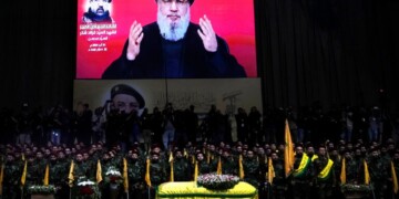 Hezbollah fighters stand behind the coffin of their top commander Fouad Shukur, who was killed by an Israeli airstrike on Tuesday, July 30, as Hezbollah leader Sayyed Hassan Nasrallah speaks through a screen during Shukur's funeral in a southern suburb of Beirut, Lebanon, Aug. 1, 2024. (AP Photo/Hussein Malla)