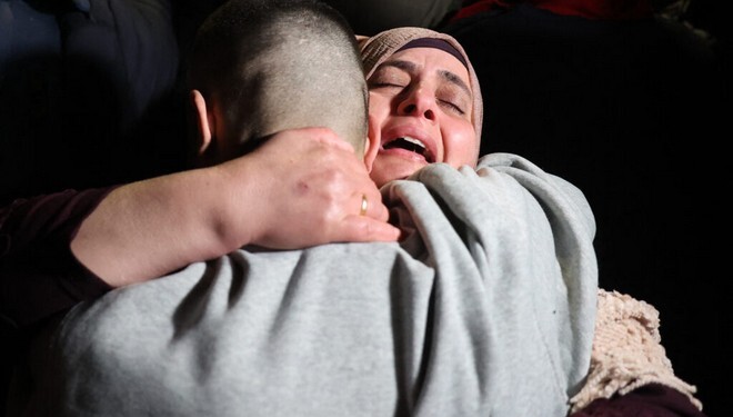 A Palestinian woman embraces her freed son upon his arrival among some 90 prisoners set free by Israel in the early hours of January 20, 2025, in the occupied West Bank town of Beitunia, on the outskirts of Ramallah. Crowds cheered, chanted and honked car horns as two buses carrying the prisoners arrived in Beitunia following their release as part of the Gaza ceasefire deal that began on January 19 and saw three Israeli hostages freed by Hamas in the Gaza Strip. (Photo by Zain JAAFAR / AFP)
