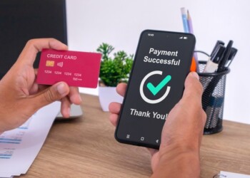 Hand holding credit card and using smartphone to make online payment. Successful payment message on smartphone screen.