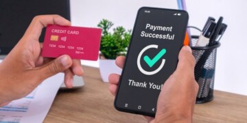 Hand holding credit card and using smartphone to make online payment. Successful payment message on smartphone screen.