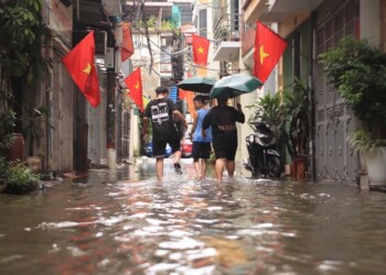 People wade through a flooded alley caused by Typhoon Kajiki in Hanoi, Vietnam, Tuesday, Aug. 26, 2025. (AP Photo/Huy Han)